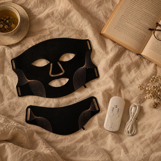 LED face and neck mask on linen bedding with a book and tea